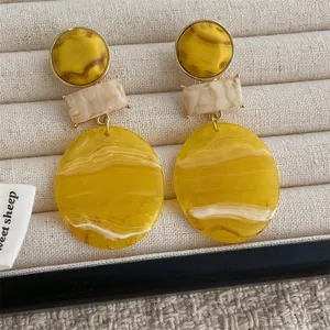 Detail view of yellow resin geometric earrings with marble texture on jewelry box