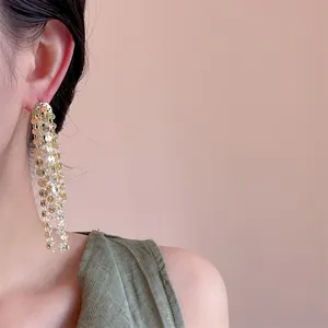 Vista detallada de pendientes largos de borla con lentejuelas doradas y cadenas finas