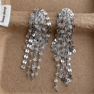 Detalle de pendientes de flecos plateados con lentejuelas brillantes y cuentas de cristal