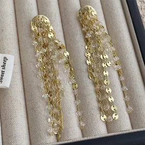 Vista macro de pendientes dorados de borla con lentejuelas y cuentas de cristal