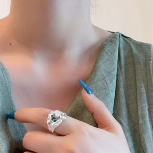 Irregular silver ring with green zircon and pearl, vintage luxury aesthetic on finger