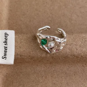 Close-up of vintage irregular silver ring with a green zircon and a white pearl detail