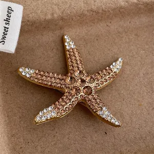 Exquisite golden starfish brooch with sparkling brown and white crystals on paper background