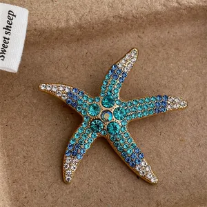 Elegant gold starfish brooch with sparkling blue and green crystals on a rustic background