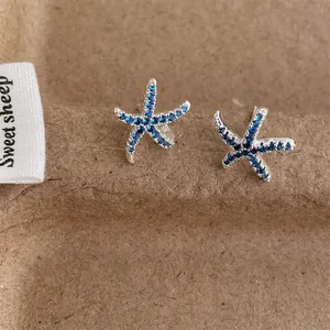Macro shot of silver starfish stud earrings featuring micro-pave blue cubic zirconia stones