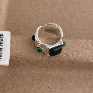 Macro detail of silver vintage ring featuring irregular lava texture and green zircon stones