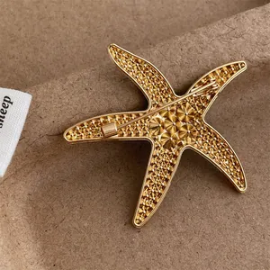 Golden starfish brooch with crystal inlay and pin clasp shown from a rear textured view