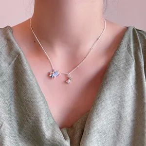 Detail van zilveren teckel ketting met blauw gestippelde hond en een klein botvormig hangertje