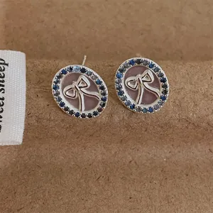 Detailopname van strik-oorbellen met paarse zirkonia op een rustieke achtergrond