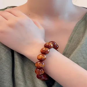 Dettaglio macro del bracciale in legno con trama di seta dorata e finitura lucida