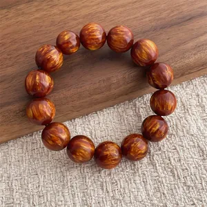 Dettaglio del bracciale in perline di legno con trama in seta dorata su legno rustico