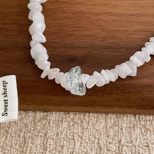 Close-up of irregular natural stones necklace with transparent crystal on wooden texture