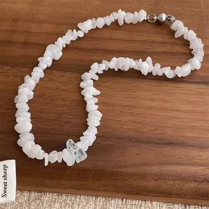 Irregular natural stone necklace with white chips and blue crystal on wood background