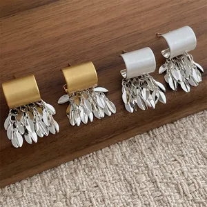 Boucles d'oreilles élégantes à pampilles feuilles or et argent sur tissu naturel