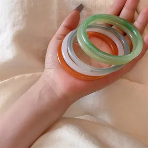 Detail of colorful translucent jade-style bangles in green, white and orange colors