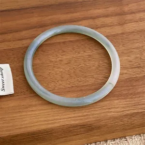 Summer style mint green resin bangle with translucent pearlescent finish on dark wood