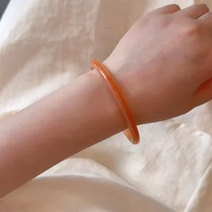 Elegant amber orange resin bangle bracelet with polished finish in minimalist style