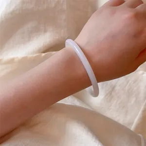 Macro view of a thin white jade bangle on wrist with elegant minimalist design