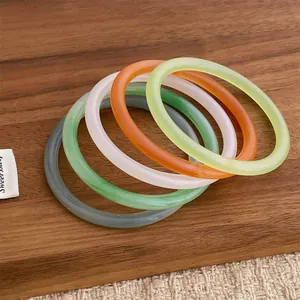 Set of 5 minimalist translucent acrylic bangles in mixed colors on a wooden surface