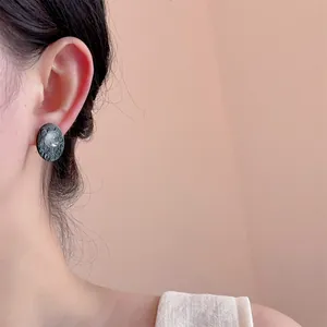 Detail of vintage oval cameo stud earrings featuring an embossed female profile on black shell