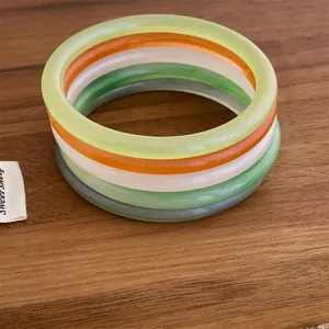 Close-up of colorful resin bracelets in green and orange with smooth translucent finish