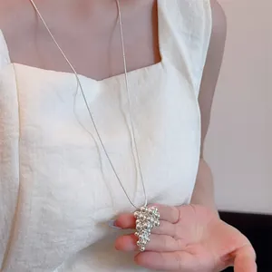 Detailed view of silver grape pendant long necklace on model with snake chain texture