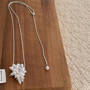 Close-up of pearl cluster pendant on silver snake chain over a rustic wooden background
