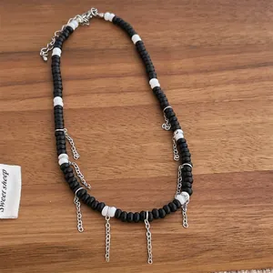 Détail du collier de perles noires et blanches avec pampilles en métal argenté suspendues