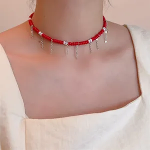 Détail du ras de cou en perles rouges et blanches avec chaînes en argent suspendues