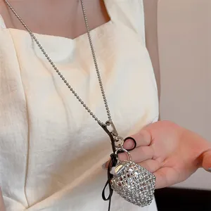 Detail van de zilveren hartvormige hanger met kristallen aan een lange kralenketting