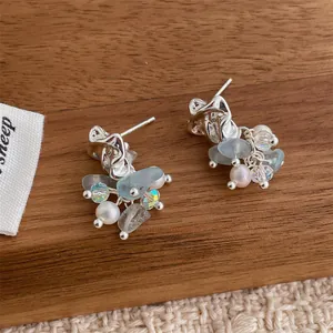 Detail of elegant silver drop earrings with natural light blue stones and pearls on wood