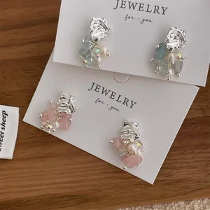 Close-up of elegant silver tassel earrings with light blue and pink natural stones
