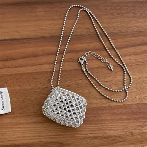 Detail van de zilveren geweven mesh tas hanger aan een lange kralenketting ketting