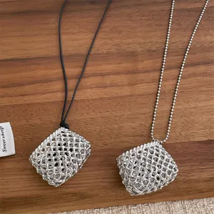 Zilveren geweven vierkante hanger ketting met zwart koord en kralenketting op hout