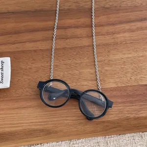 Detailed view of silver metal chain on retro black round glasses over a wood tray