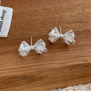 Macro view of silver bow stud earrings with sparkling cubic zirconia and pleat textures