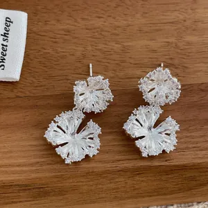 Macro shot of silver flower earrings with pavé set cubic zirconia on wood background
