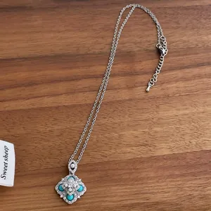 Macro view of flower necklace pendant with turquoise, white pearls and silver chain