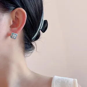 Elegant four-leaf clover stud earrings with blue gemstones and pearls on model