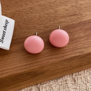 Detail view of pink round stud earrings with smooth finish on a wooden display