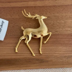 Close-up of a polished gold elk brooch on a minimalist rustic wooden background