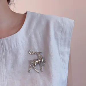 Polished silver elk brooch pin with jumping reindeer design on a grey blazer lapel