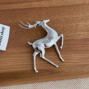 Detailed view of silver moose brooch with high-polish finish on a wooden display