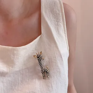 Detailed shot of a giraffe brooch with faux pearls and black and white enamel on a coat