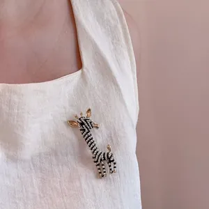 Elegant gold zebra brooch with black enamel stripes and white pearls on linen clothing