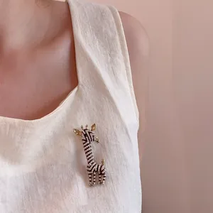 Detailed view of a gold giraffe brooch with micro pearls and enamel on a linen garment