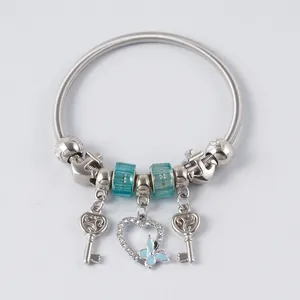 Macro shot of silver-toned spring bracelet with blue beads and heart butterfly pendant