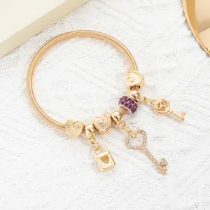 Detail of gold elastic charm bracelet with heart keys and purple crystal beads