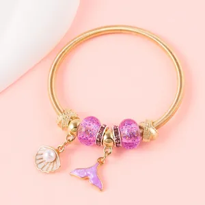 Detail of gold spring bracelet with purple beads and white shell pendant charms
