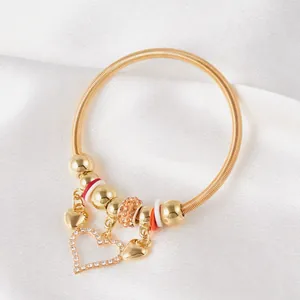 Detail of gold spring bracelet with orange crystal beads and heart-shaped pendants